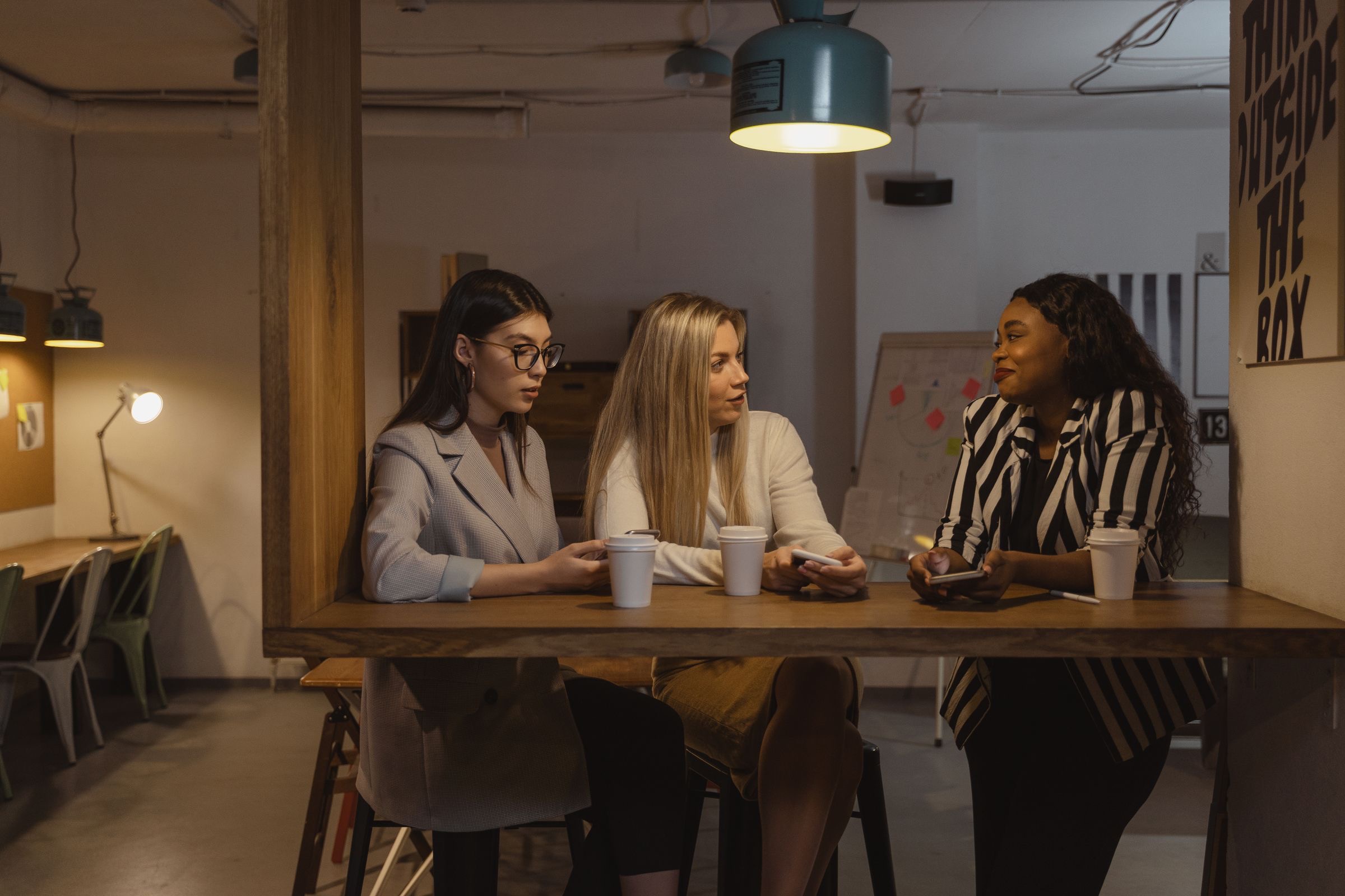 Compañeras de trabajo conversando con café en un coworking